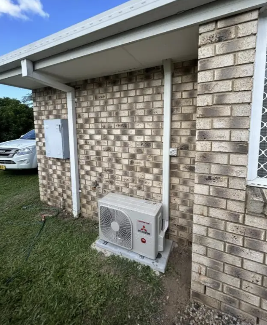 Split-system outdoor unit installed on a concrete pad beside a brick home